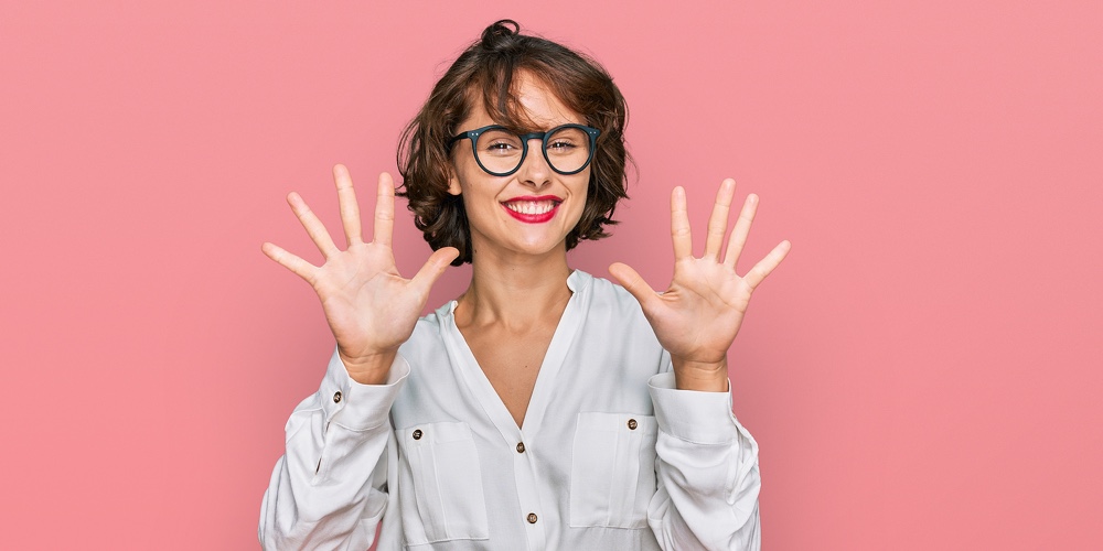 Young hispanic woman wearing business style and glasses showing and pointing up with fingers number