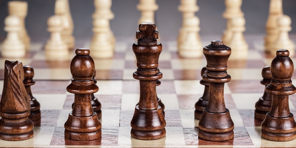 Financial Advisor Talking To Senior Couple At Home|chess board with figures on the wooden table