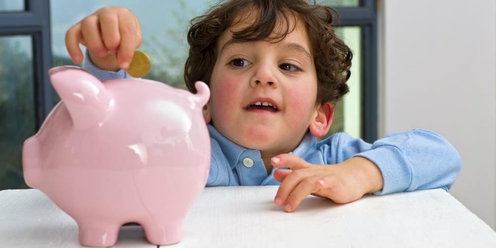 bigstock-young-boy-holding-a-piggy-bank-19485962