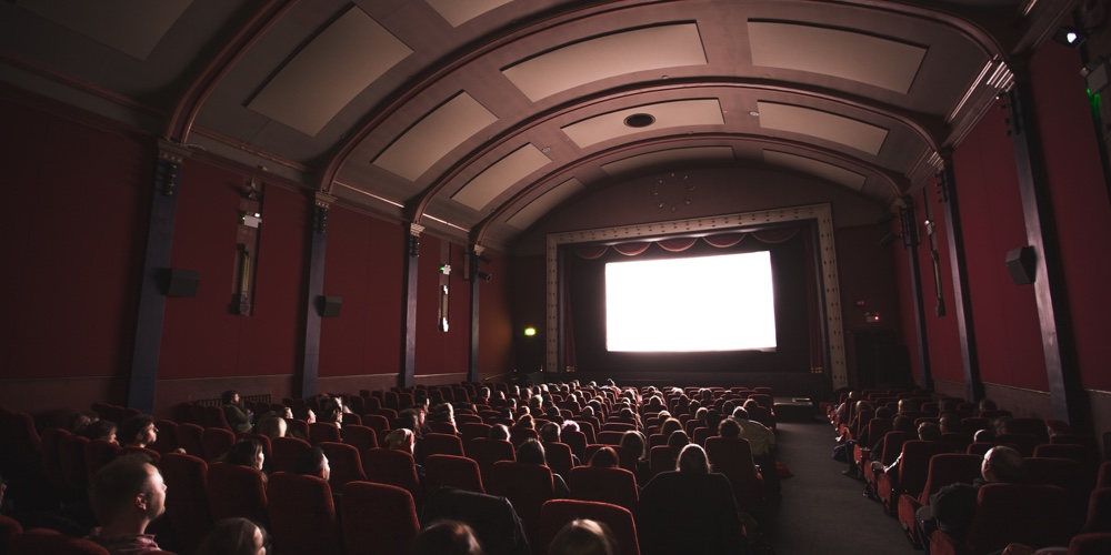 jake-hills-23LET4Hxj_U-unsplash|Movie projector with light beam and film reels on dark backgroun