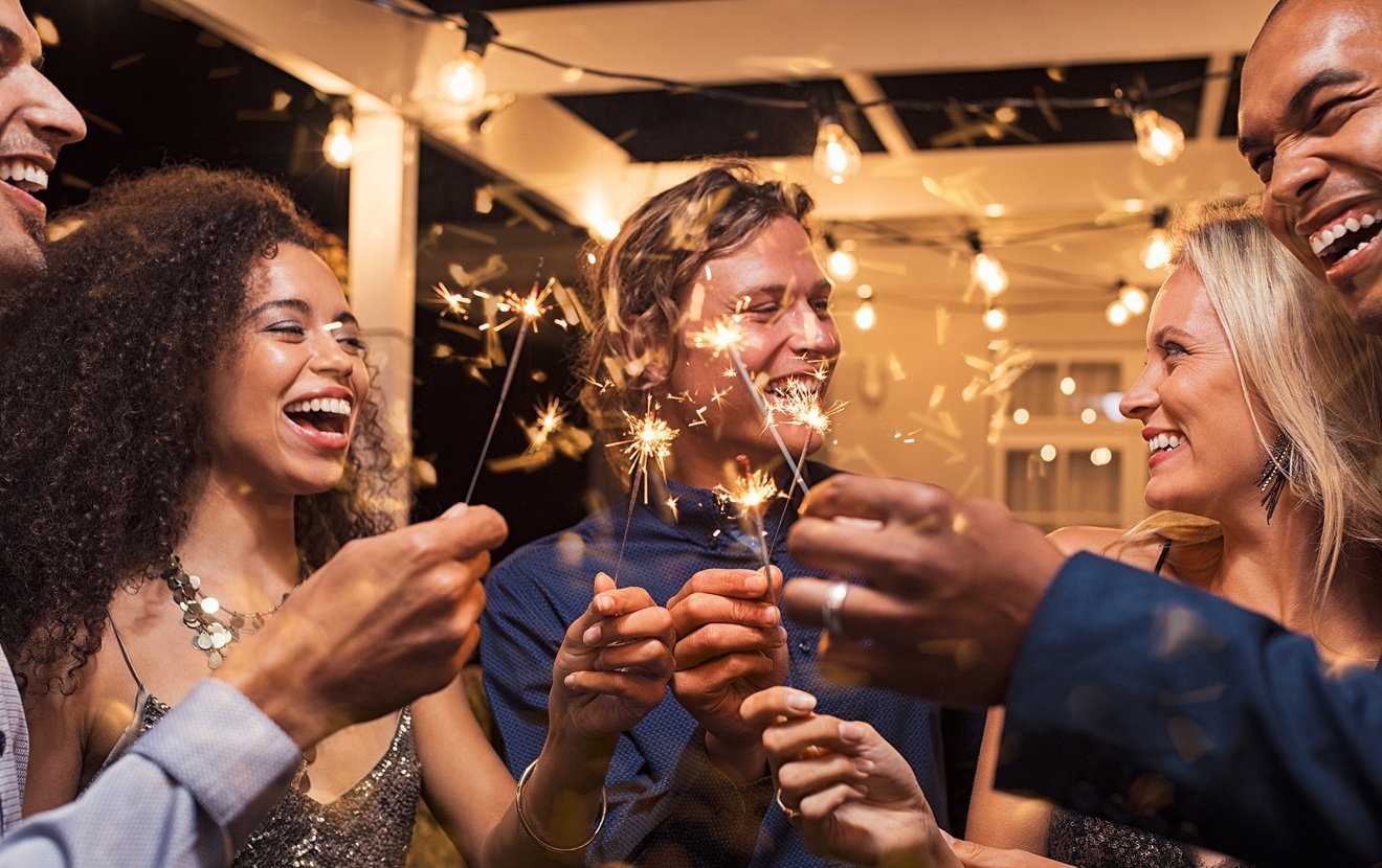 Friends celebrating christmas with bengal lights. Group of elegant women and men celebrating new yea