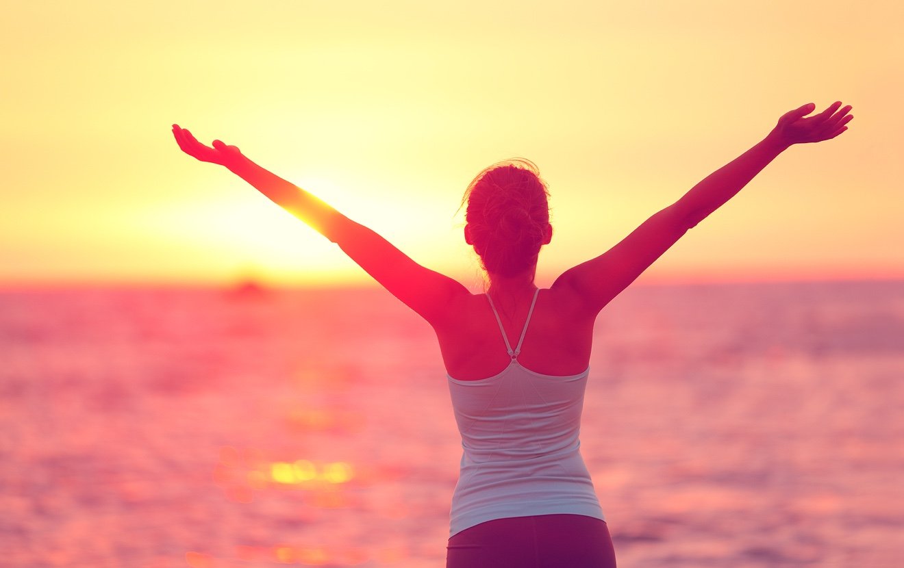 Wellness, well-being and happiness concept. Silhouette of woman with open arms raised to the sky on