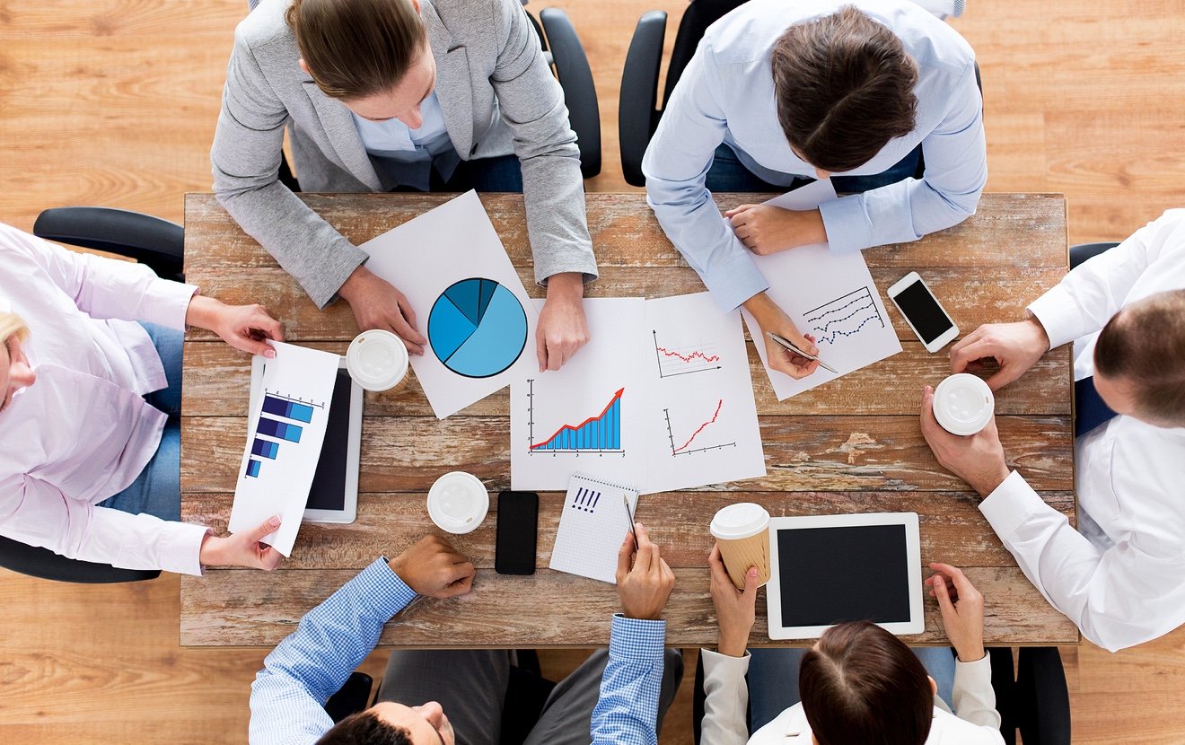 business, people, statistics and team work concept – close up of creative team with charts and gadge