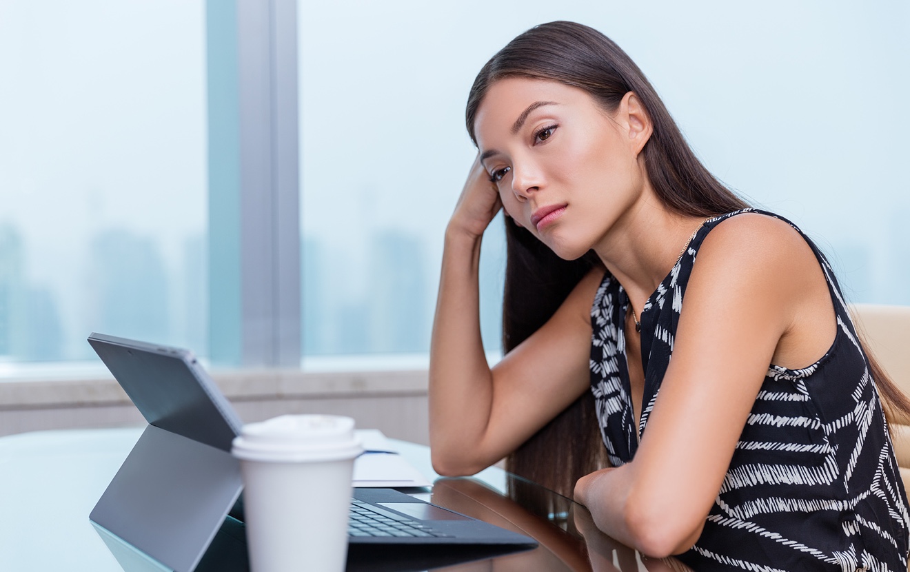 Bored or sad woman working at office job. Negative work concept. Tired businesswoman sitting at desk