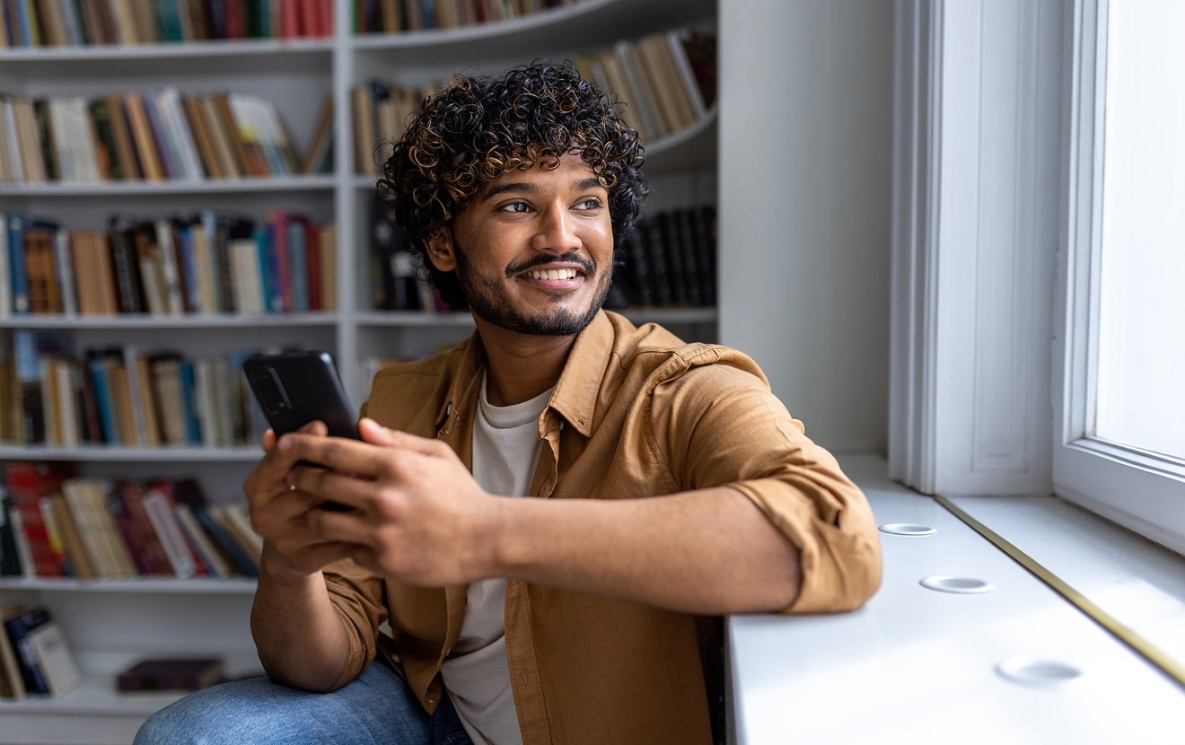 Close Up Portrait Of Young Successful Hispanic Student, Man With Curly Hair Looking Out Window Smili