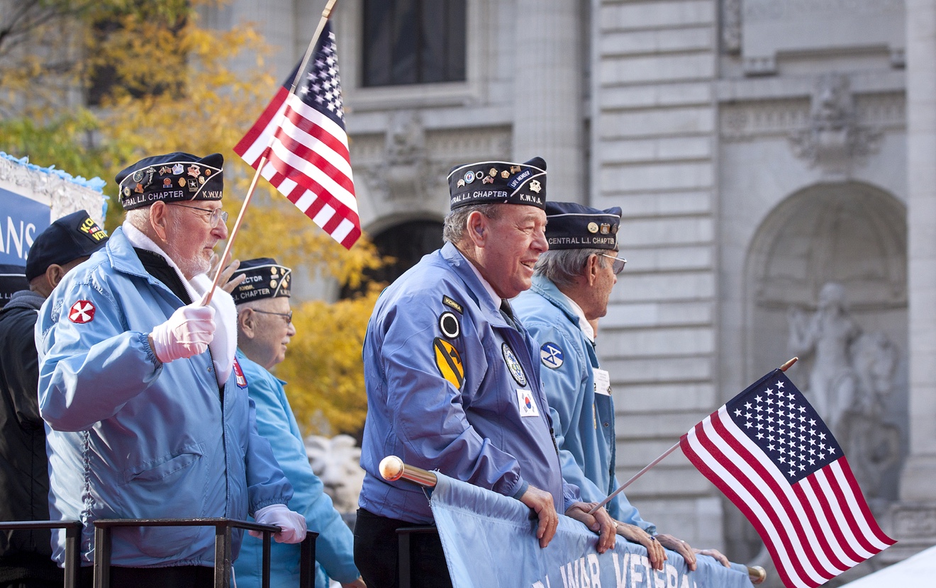 NEW YORK – NOV 11, 2014: US vets wave American Flags as they stand on a parade float in the 2014 Ame