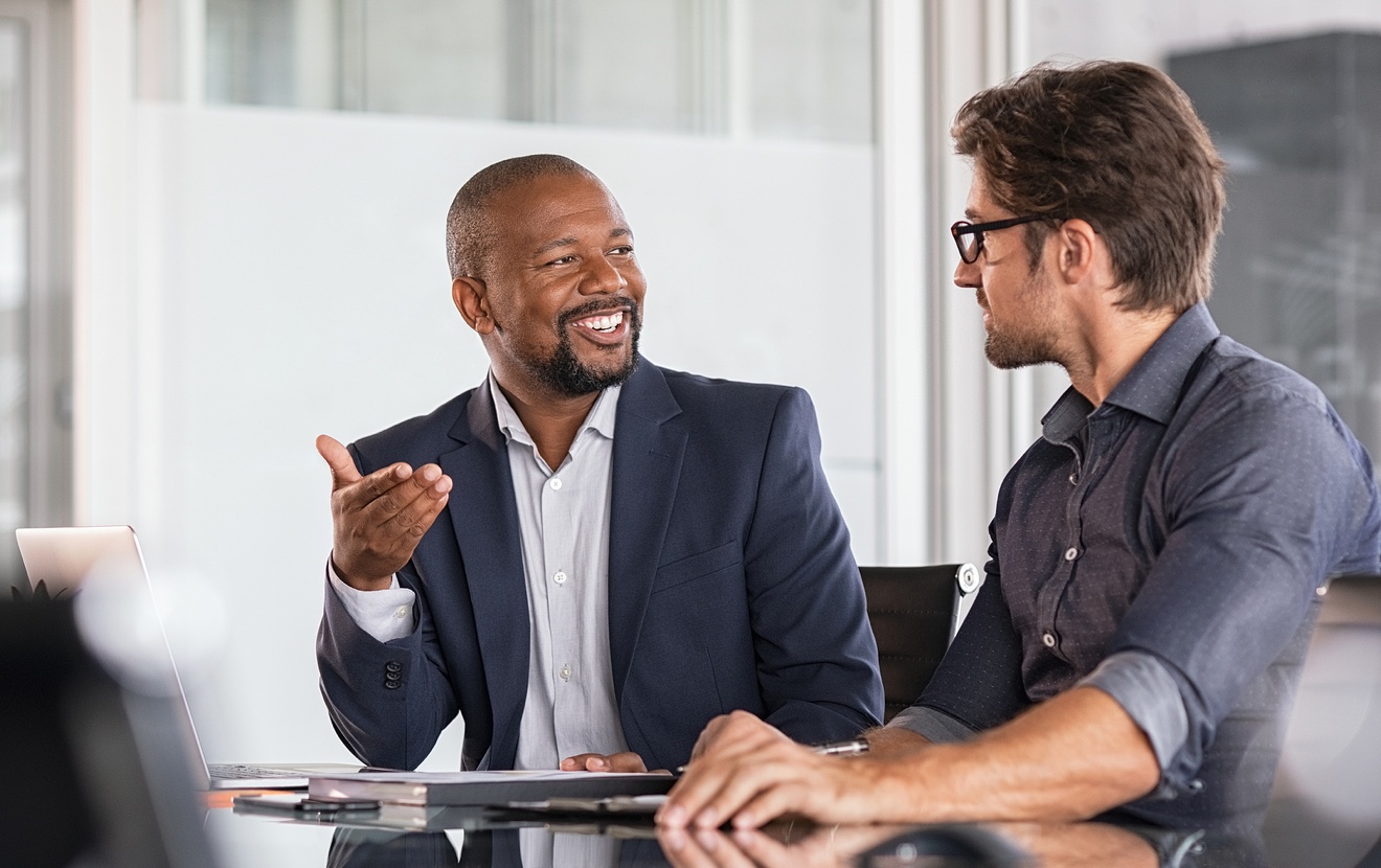 Two happy business colleagues at meeting in modern office interior. Successful african boss in a con