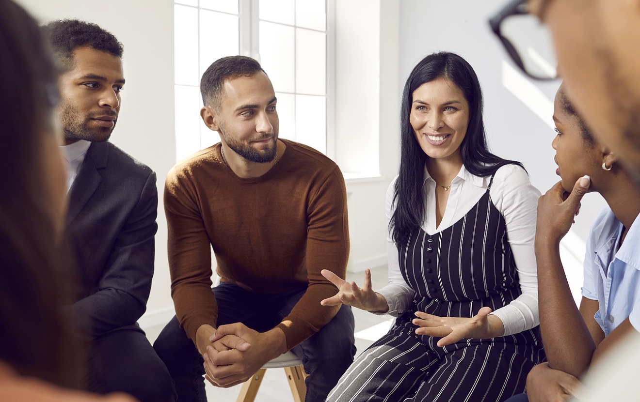Female Coach Or Team Leader Tells Funny Story Or Joke To Diverse Team During Work Meeting.