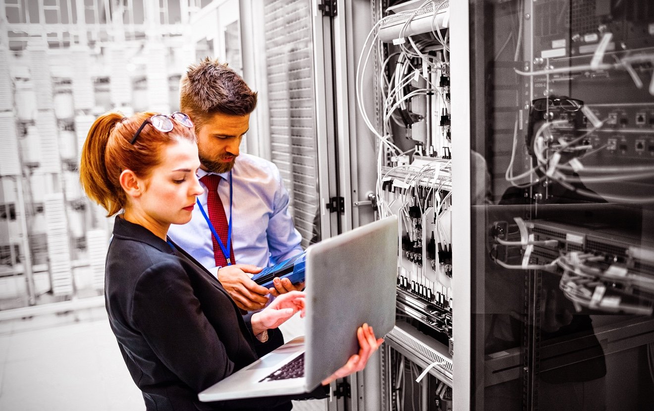 Technicians using laptop while analyzing server in server room