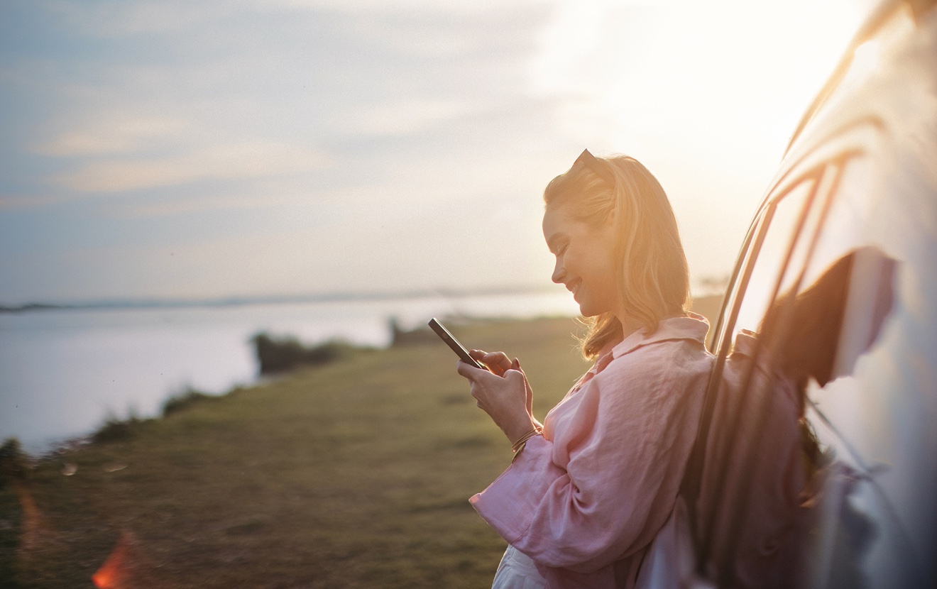 Young Woman Scrolling Phone, Leaning On Her Car In Nature,
