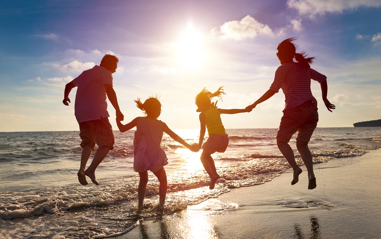 Happy Family Jumping Together On The Beach