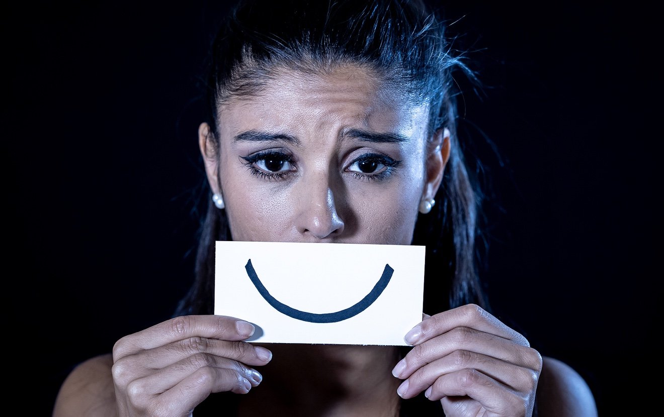 Young Woman Suffering From Depression Hiding Her Sadness And Sorrow Behind A Drawn Smile